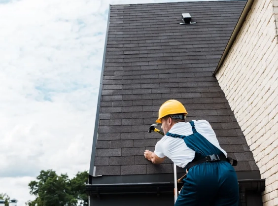 repairman in uniform and helmet repairing roof